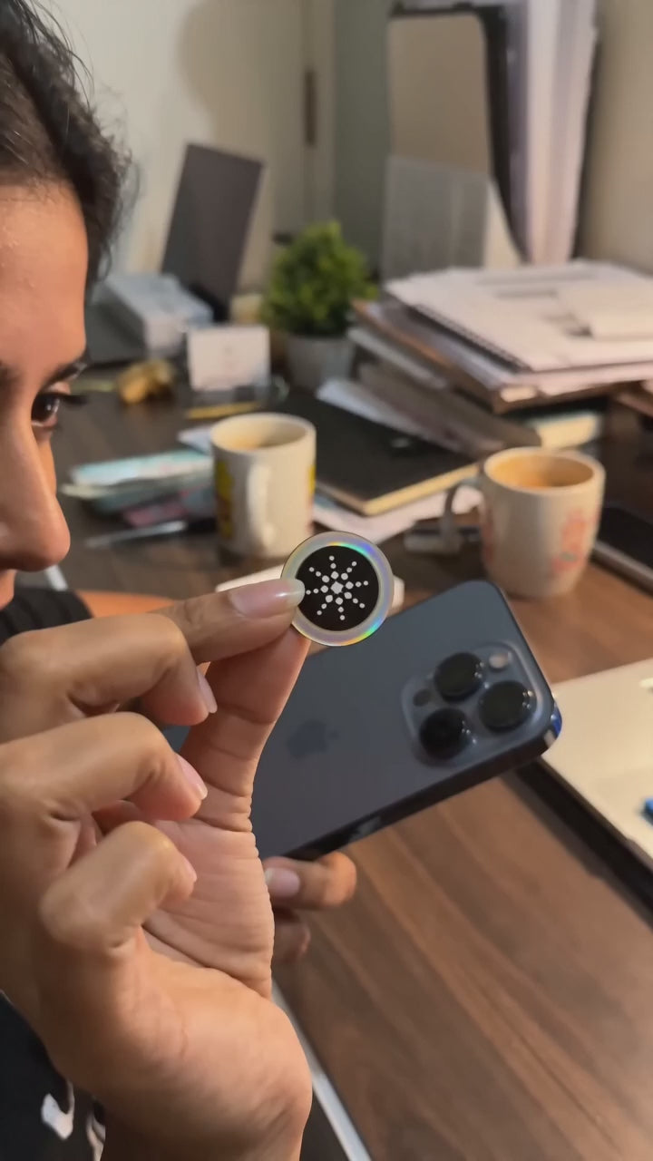 Indian customer peeling a QuietField EMF chip and sticking it on her phone at a home desk