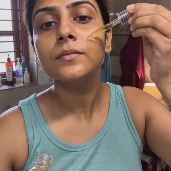 Indian woman presses golden serum drops onto cheek, glass-skin glow, real customer UGC